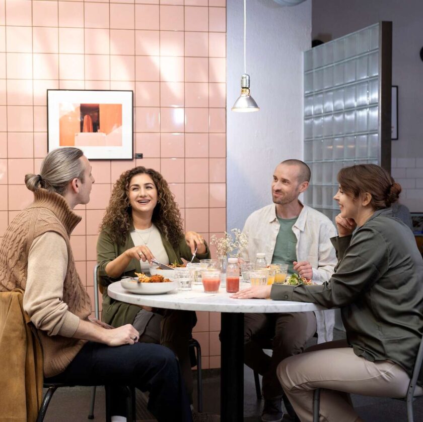 Fyra personer sitter runt ett bord på en restaurang och pratar.