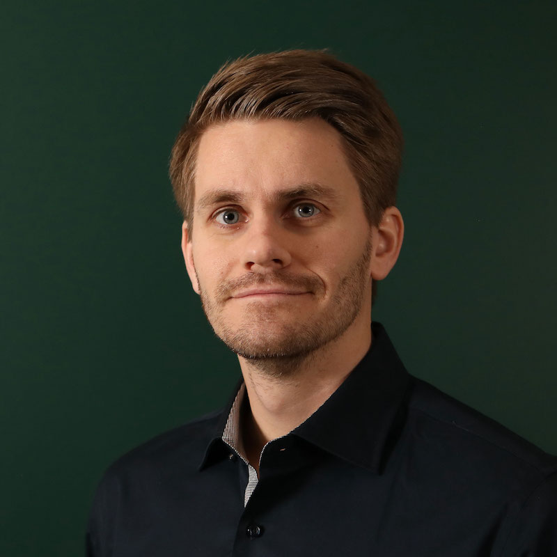 En person med skjorte smiler, bakgrunn er grønn.