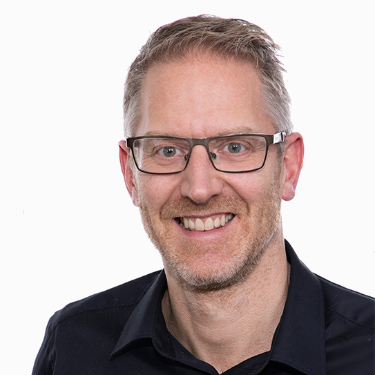 Man i glasögon med kort hår som ler mot kameran.