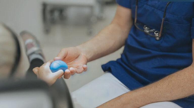 Tannlege gir barn en blå stressball på klinikk, barnets hånd og tannlegens hånd vises.